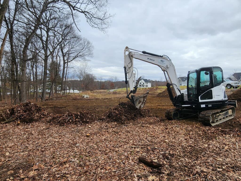 A bulldozer is digging a hole in a field covered in leaves.