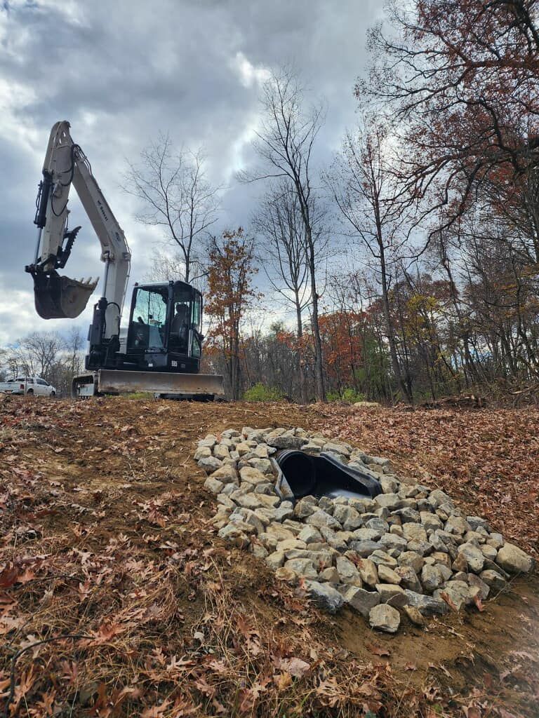 An excavator is digging a hole in the ground in the middle of a field.