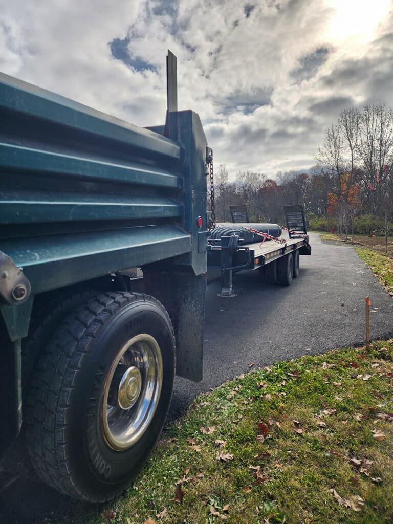 A dump truck with a trailer attached to it is parked on the side of the road.