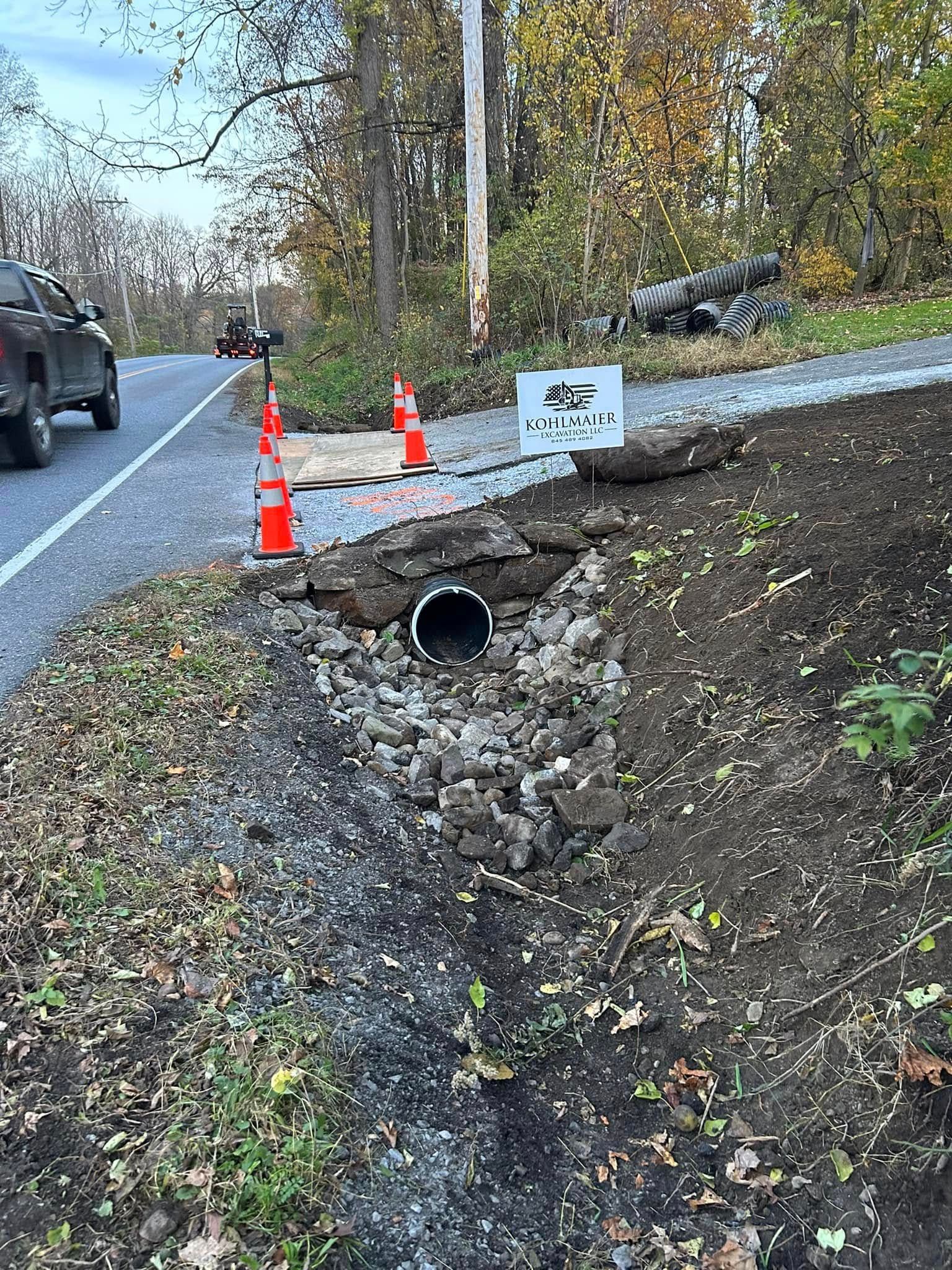 A car is driving down a road next to a hole in the ground.