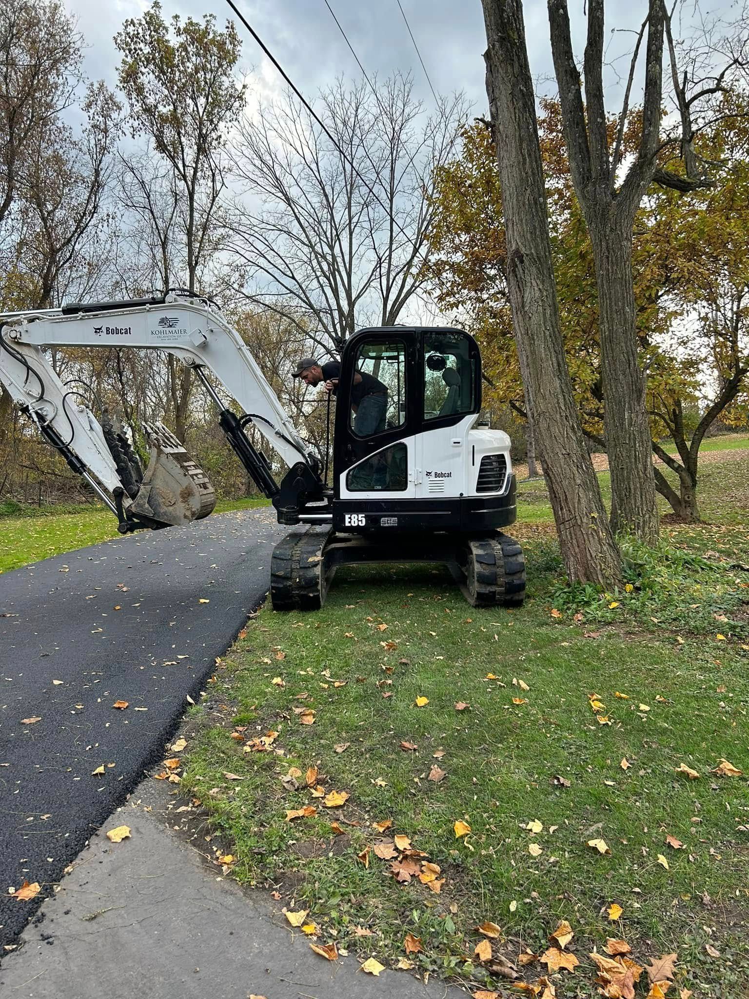 A white and black excavator is parked on the side of a road.