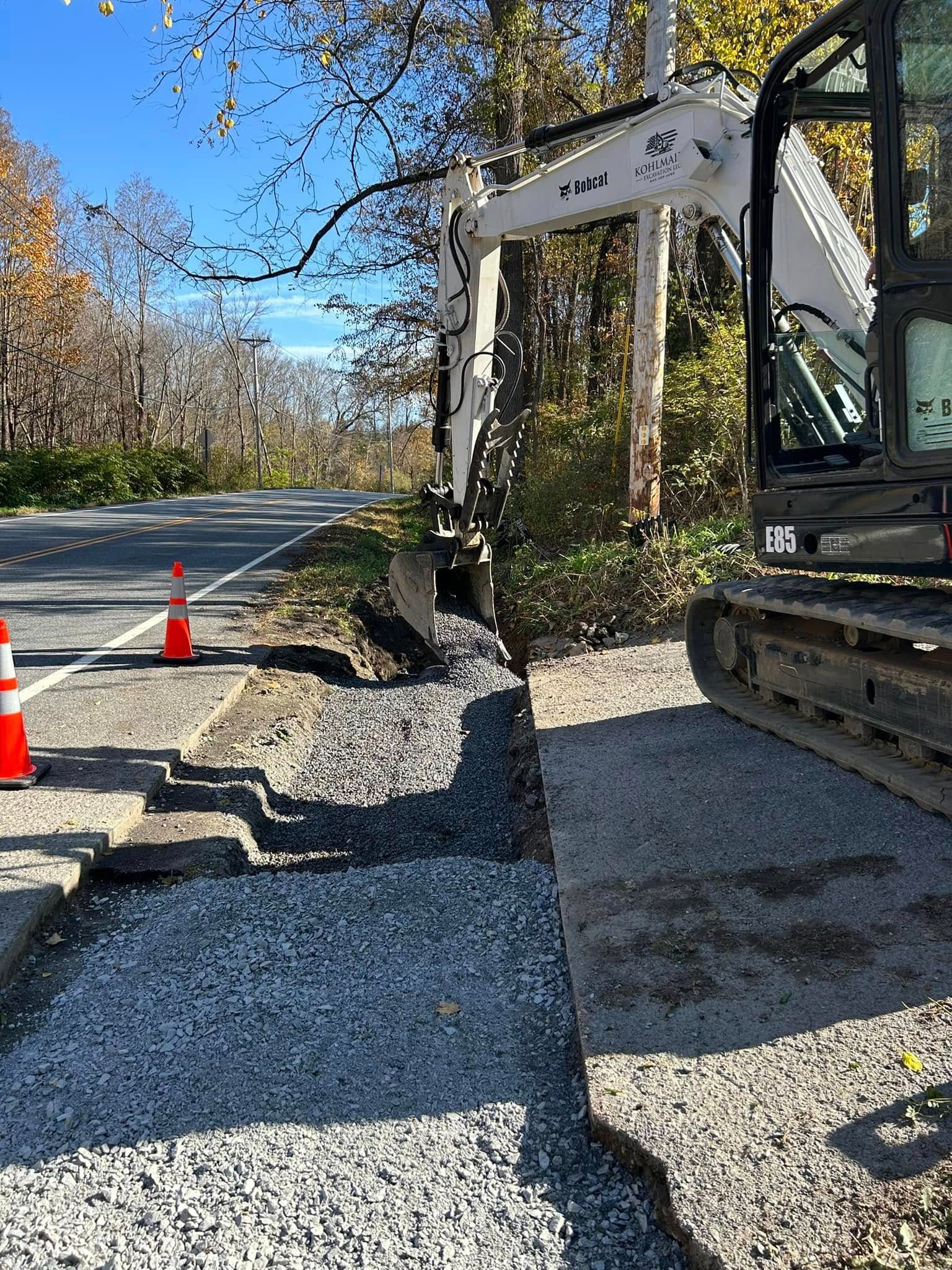 A bulldozer is digging a hole in the ground next to a road.