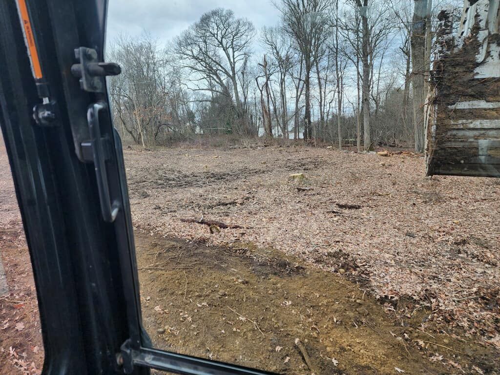 A view of a field through the window of a bulldozer.