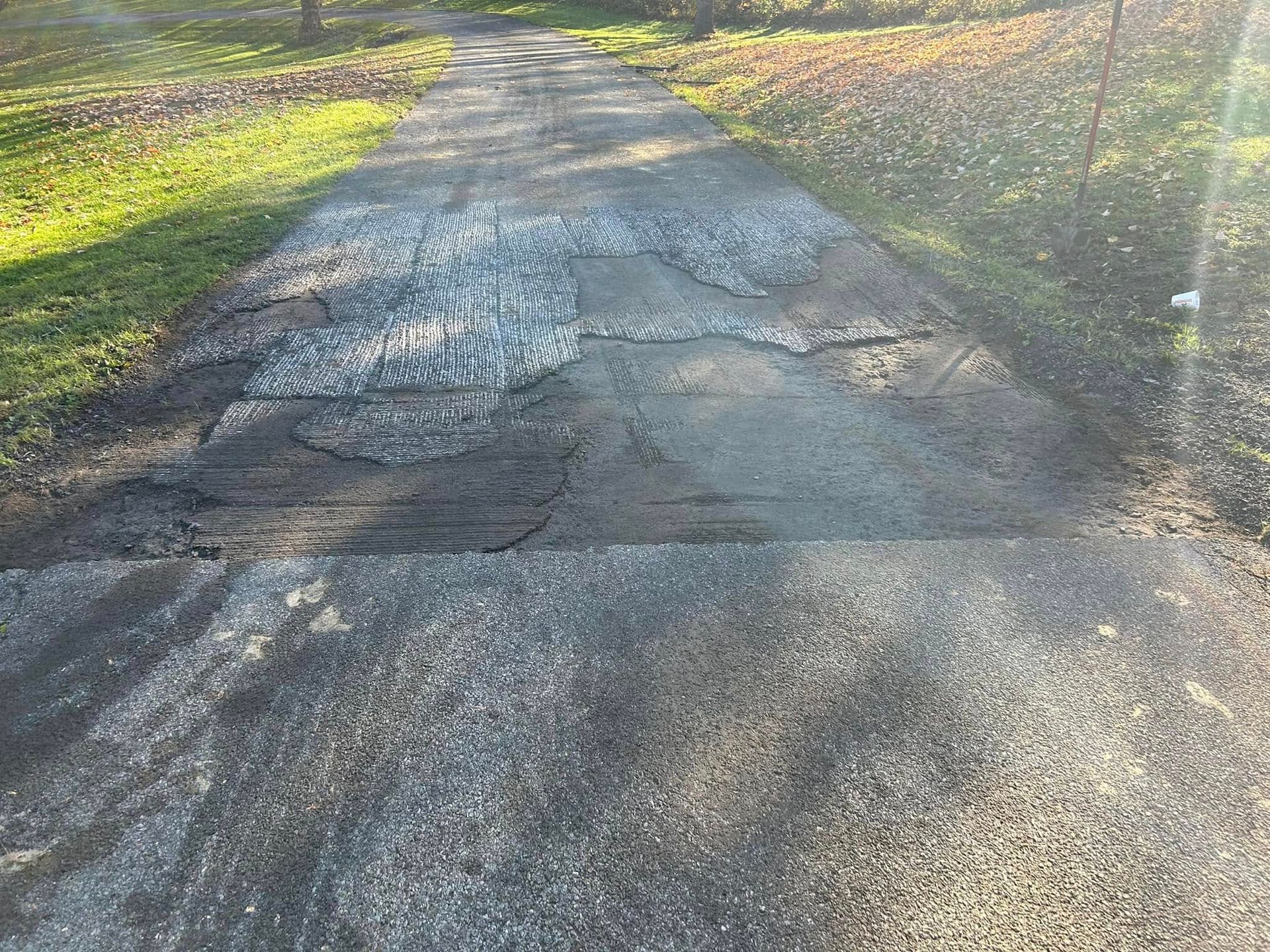 A very narrow road with a lot of potholes on it.