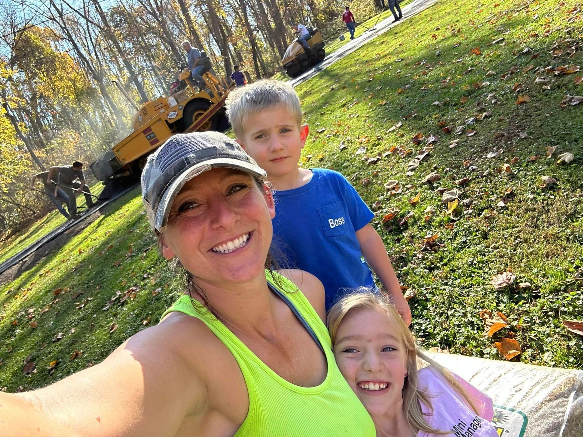 A woman is taking a selfie with two children in a park.
