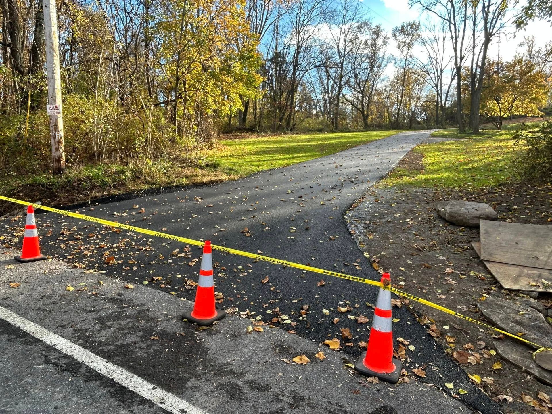 Three orange and white traffic cones are sitting on the side of a road.