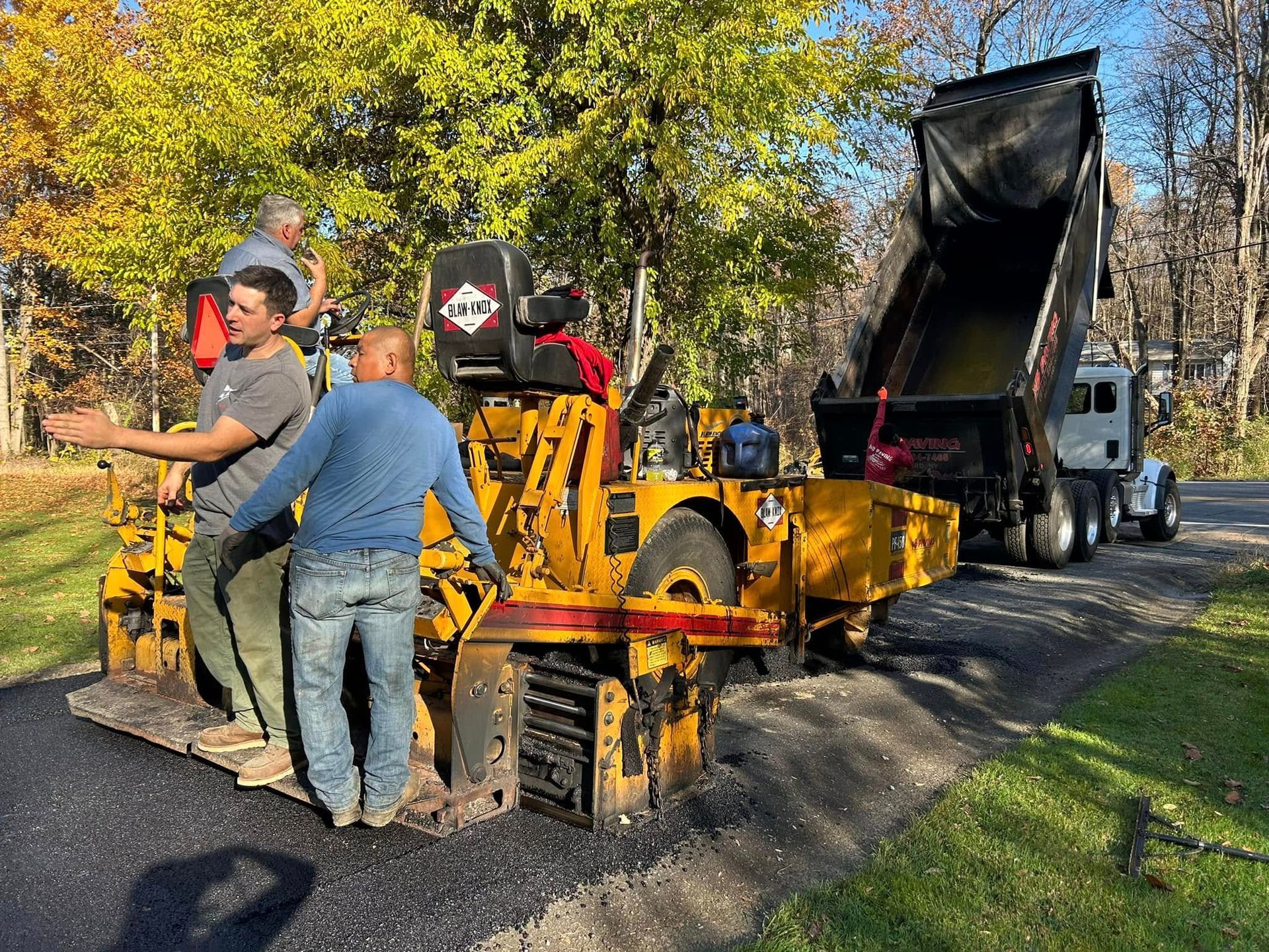 A group of men are standing next to a machine on a road.