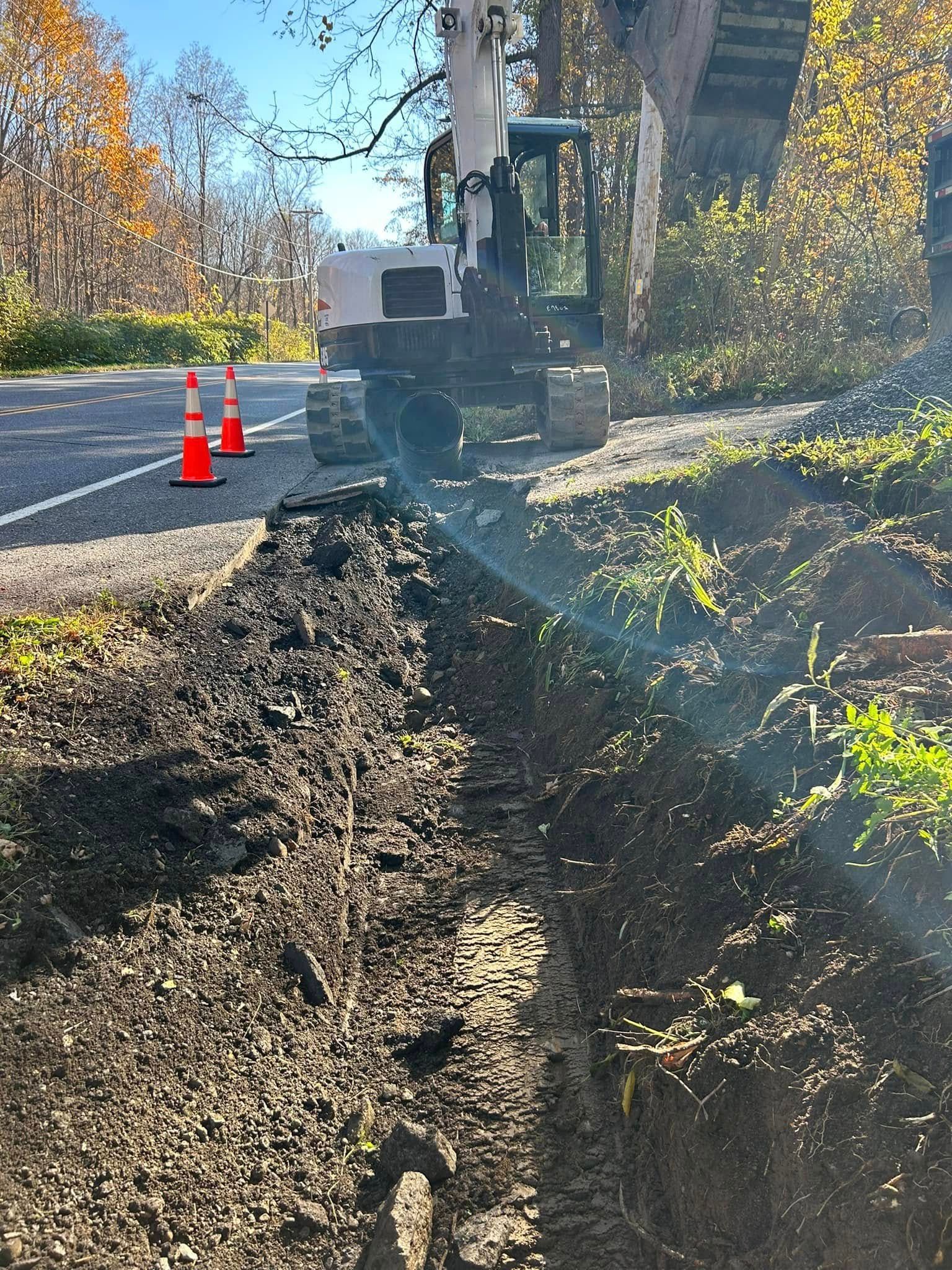 A bulldozer is digging a hole in the ground next to a road.