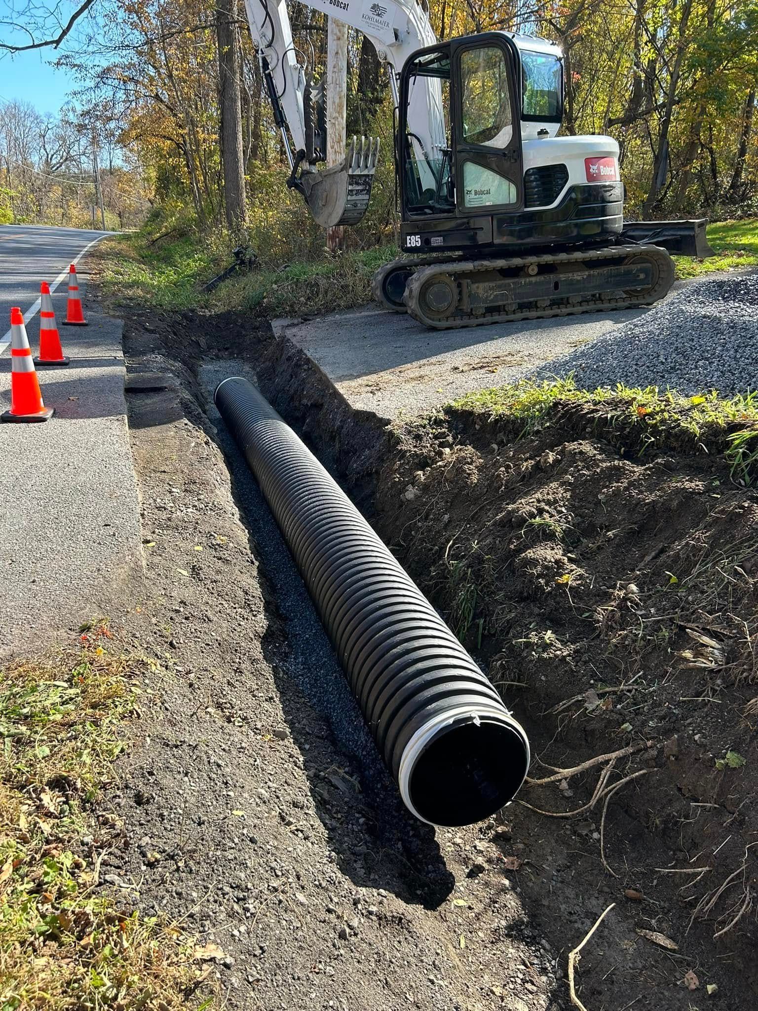 A large black pipe is sitting in the dirt next to a bulldozer.