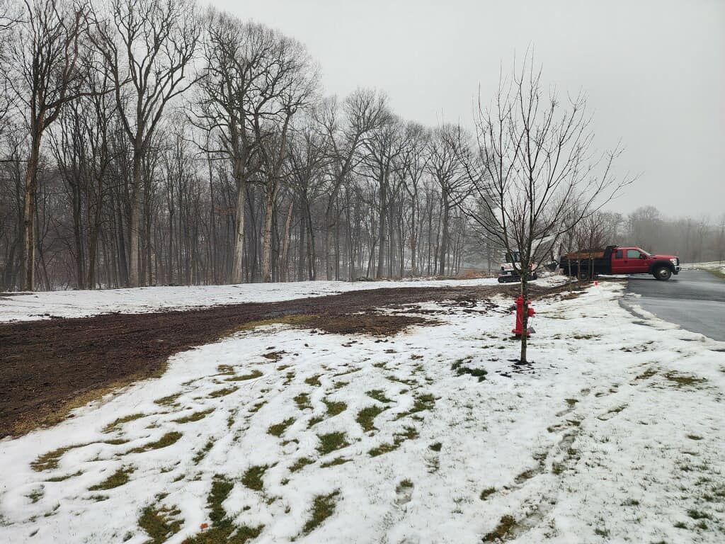 A red truck is parked on the side of the road in the snow.