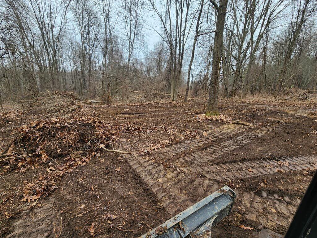 A person is driving a bulldozer through a muddy forest.