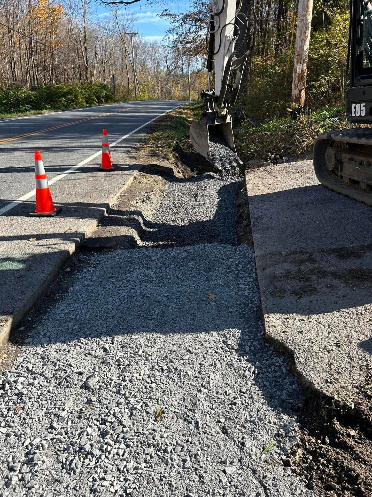 A bulldozer is working on a gravel road next to a road.