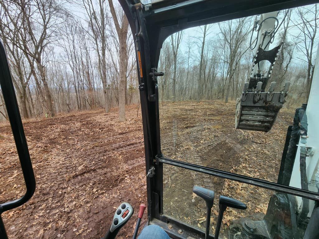 A person is driving a bulldozer in the woods.