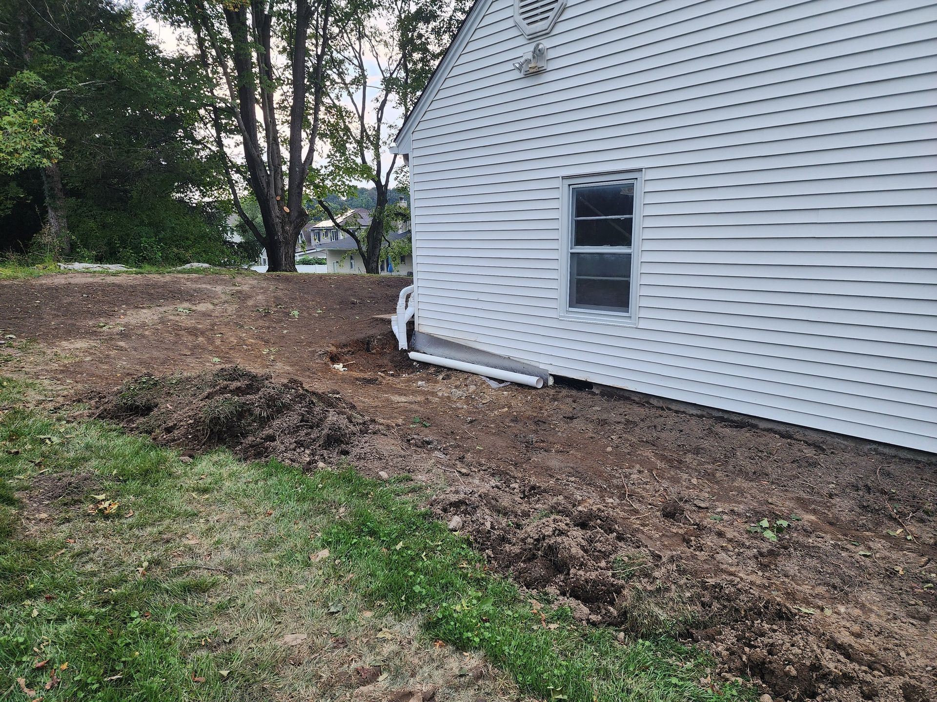 A white house with a lot of dirt in front of it.
