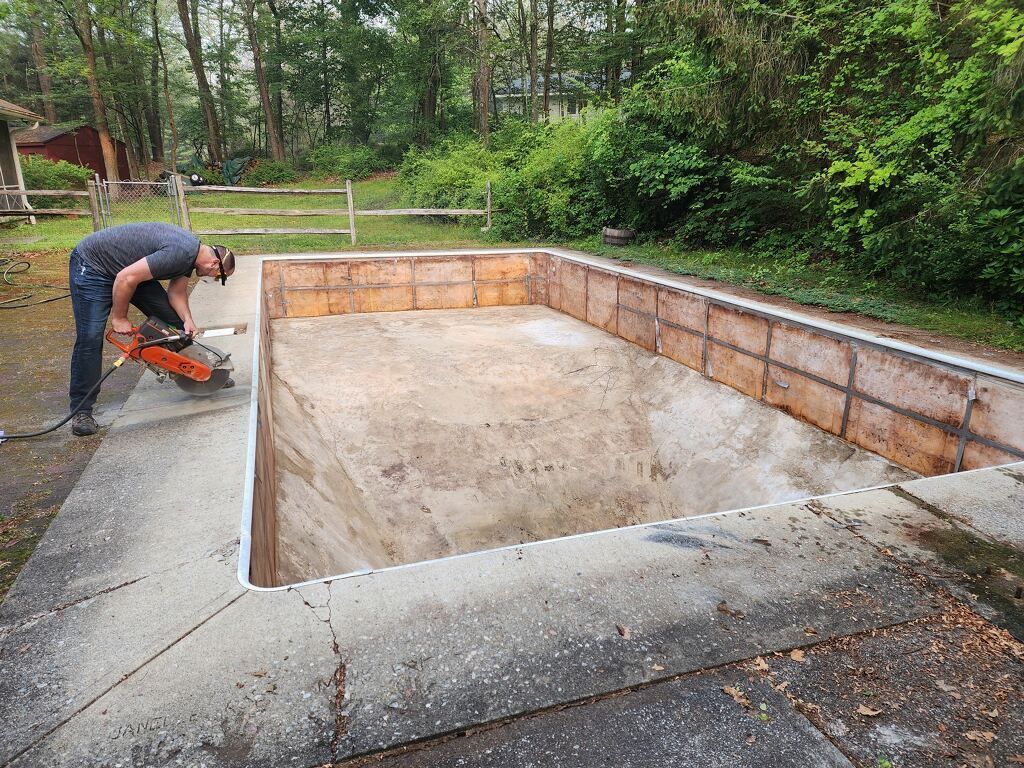A man is cutting concrete in a pool with a saw.