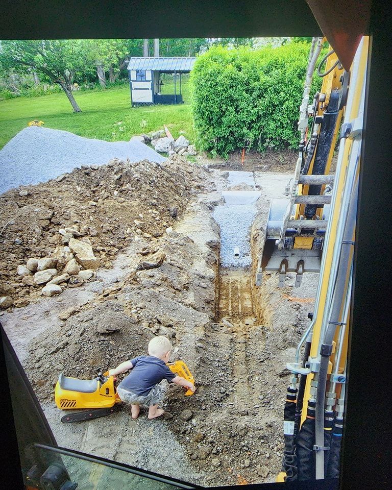 A little boy is playing with a toy excavator in the dirt.