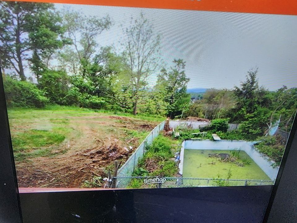 A computer screen shows a picture of a fenced in yard surrounded by trees.
