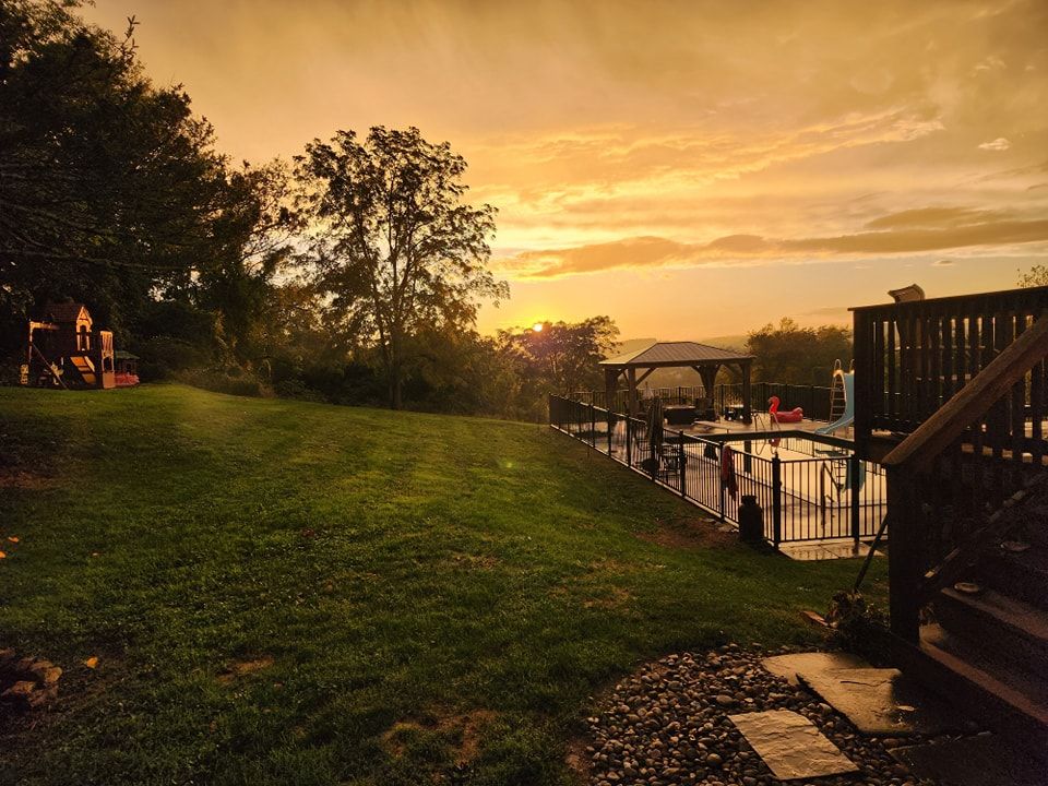 A backyard with a deck and a gazebo at sunset