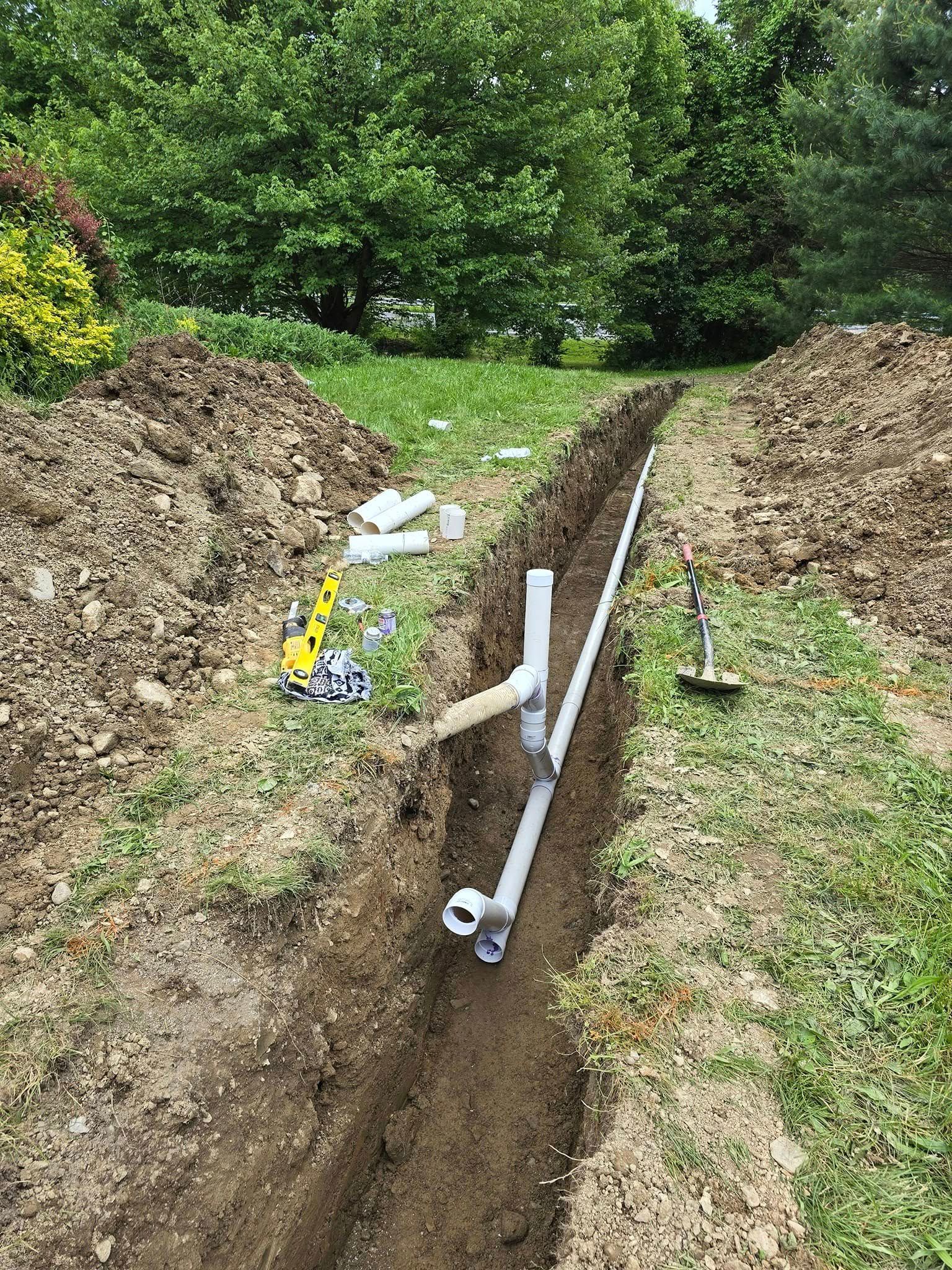 A drain pipe is being installed in a trench in a yard.