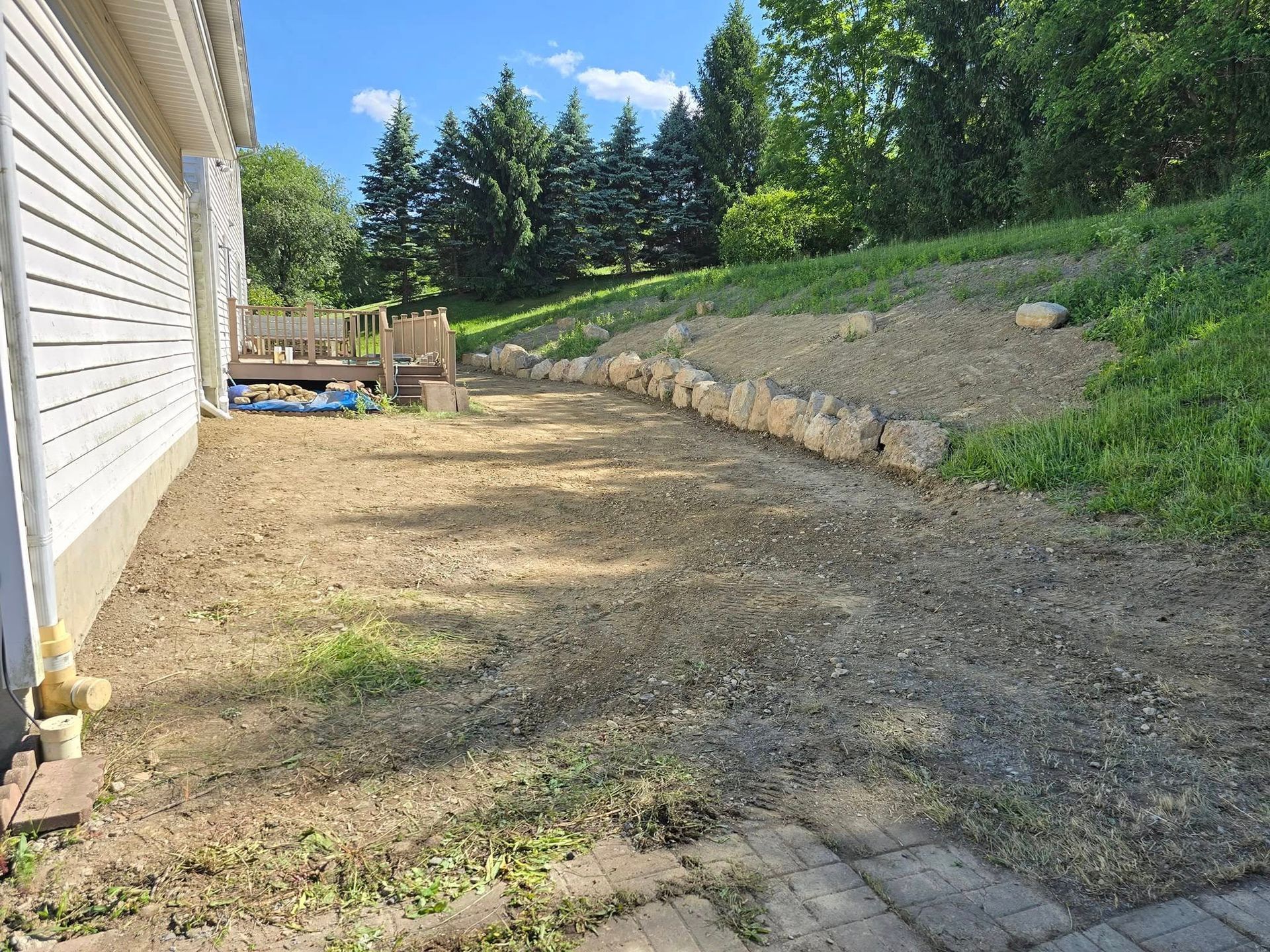 A dirt path leading to a house with trees in the background.