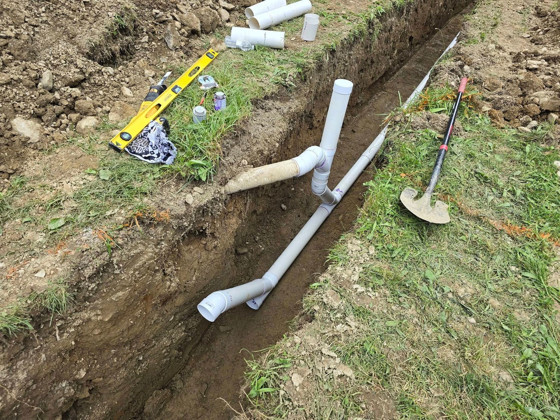 A drain pipe is being installed in a trench.