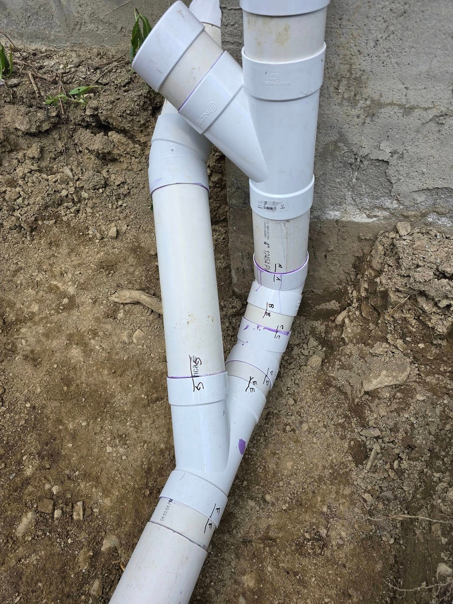 A couple of white pipes sitting on top of a dirt ground.