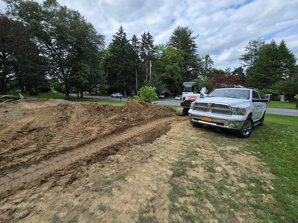 A white truck is parked next to a bulldozer in a dirt field.