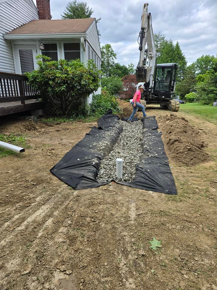A man is digging a trench in the dirt in front of a house.