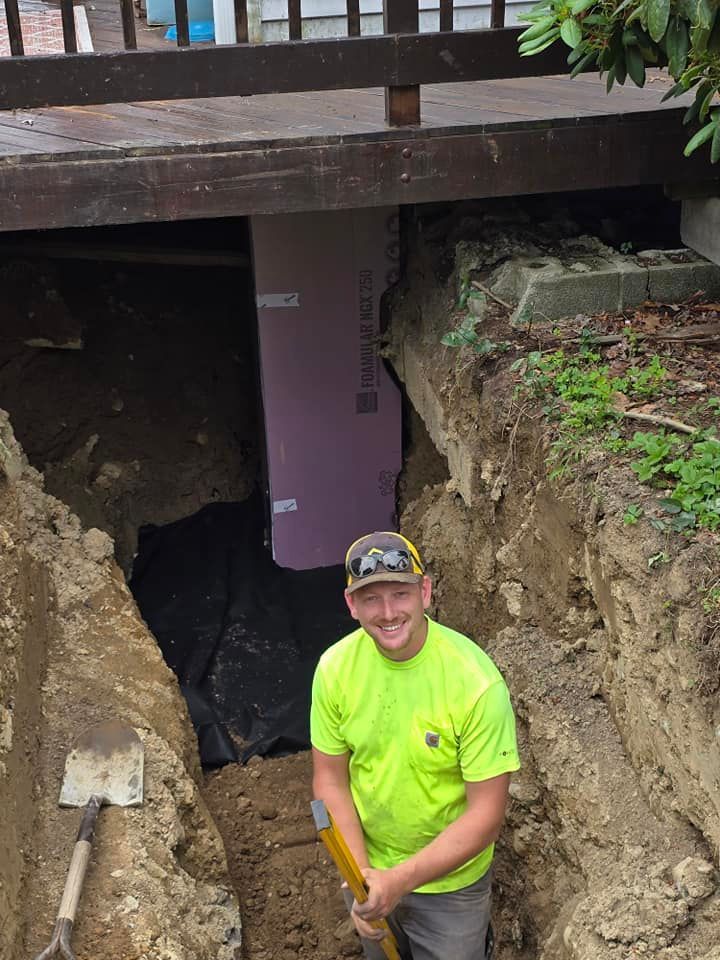 A man is standing in a hole holding a shovel.