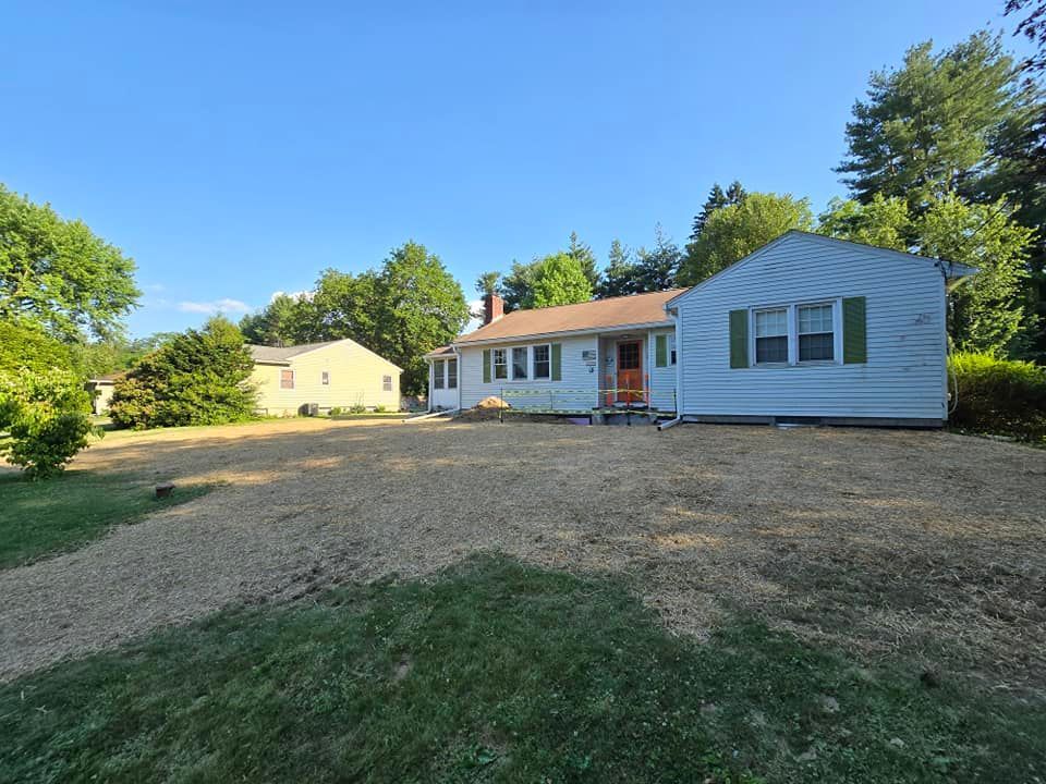 A white house is sitting on top of a gravel driveway.