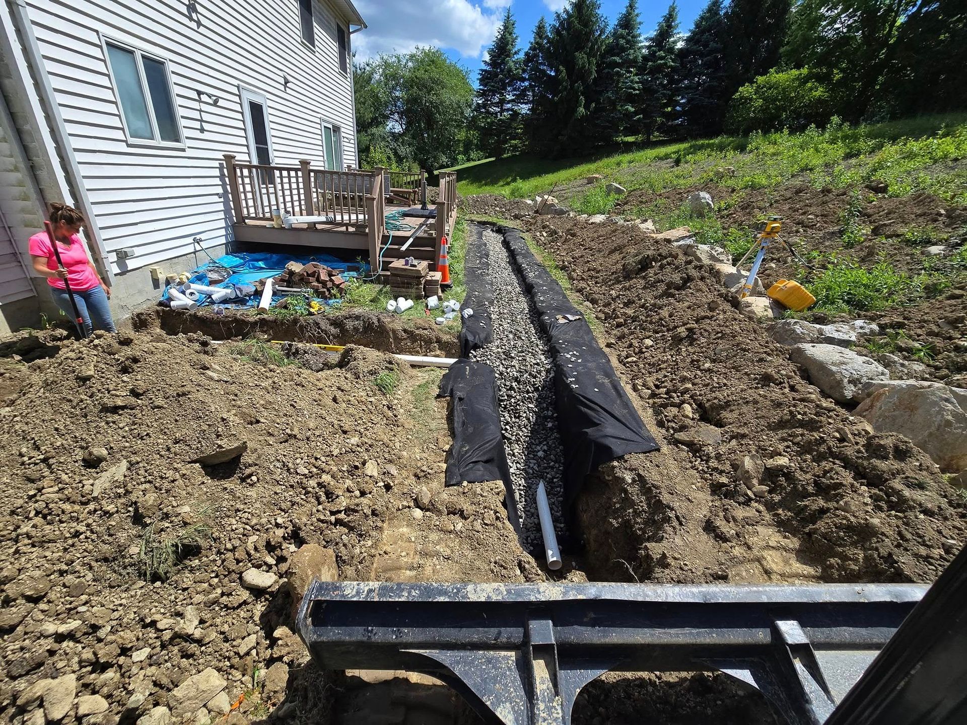 A woman is standing in a pile of dirt in front of a house.