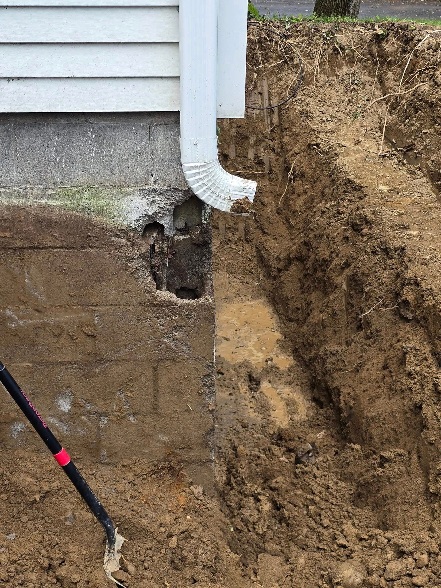 A shovel is digging a hole in the ground next to a house.