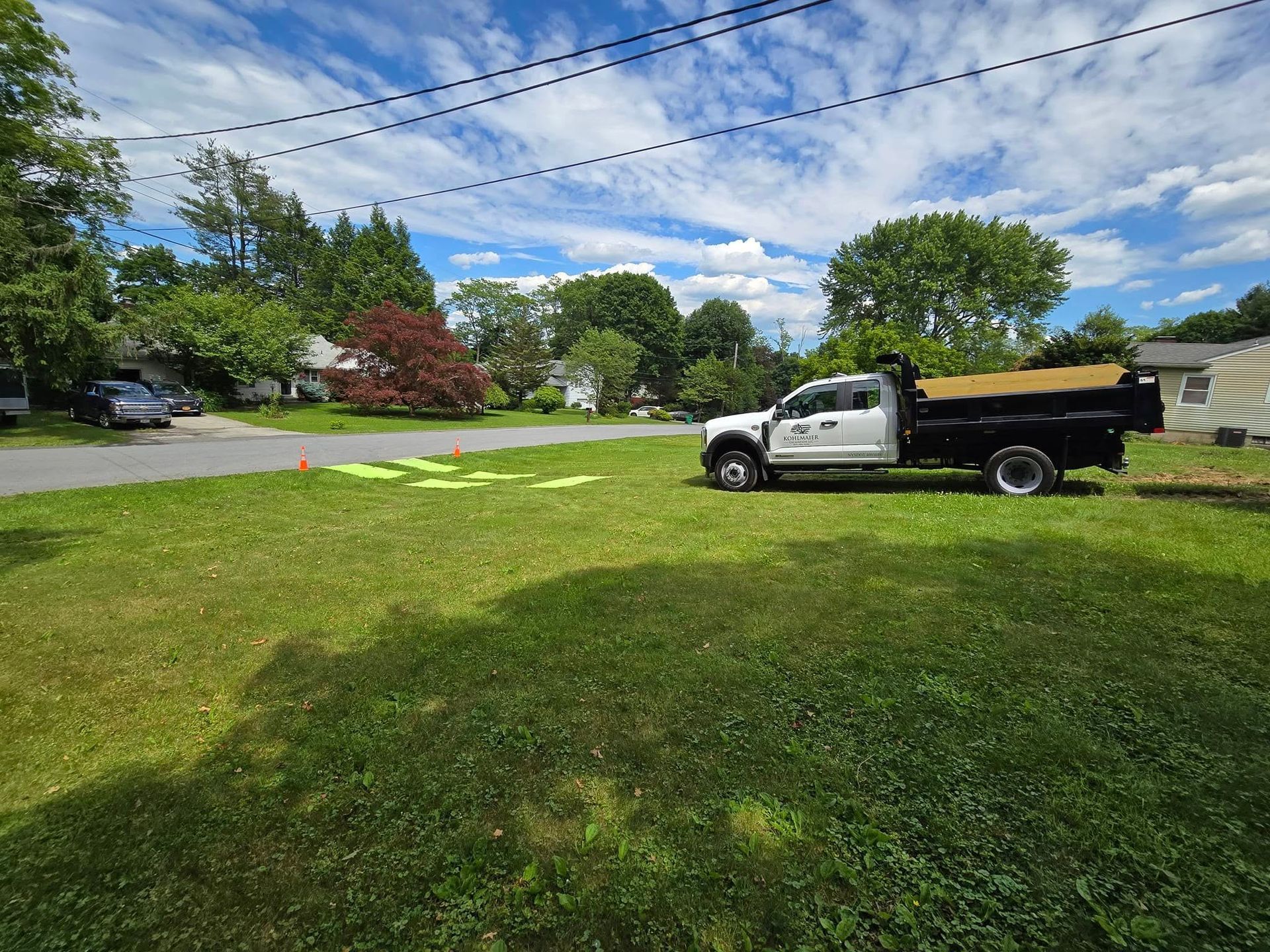 A white dump truck is parked in a grassy yard.