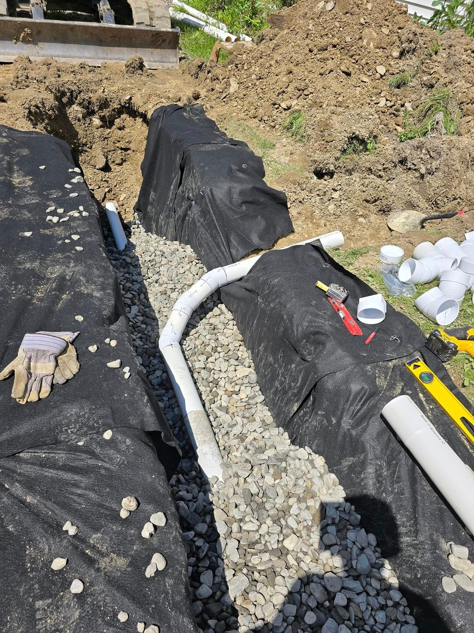 A pipe is being installed in a trench in the ground.