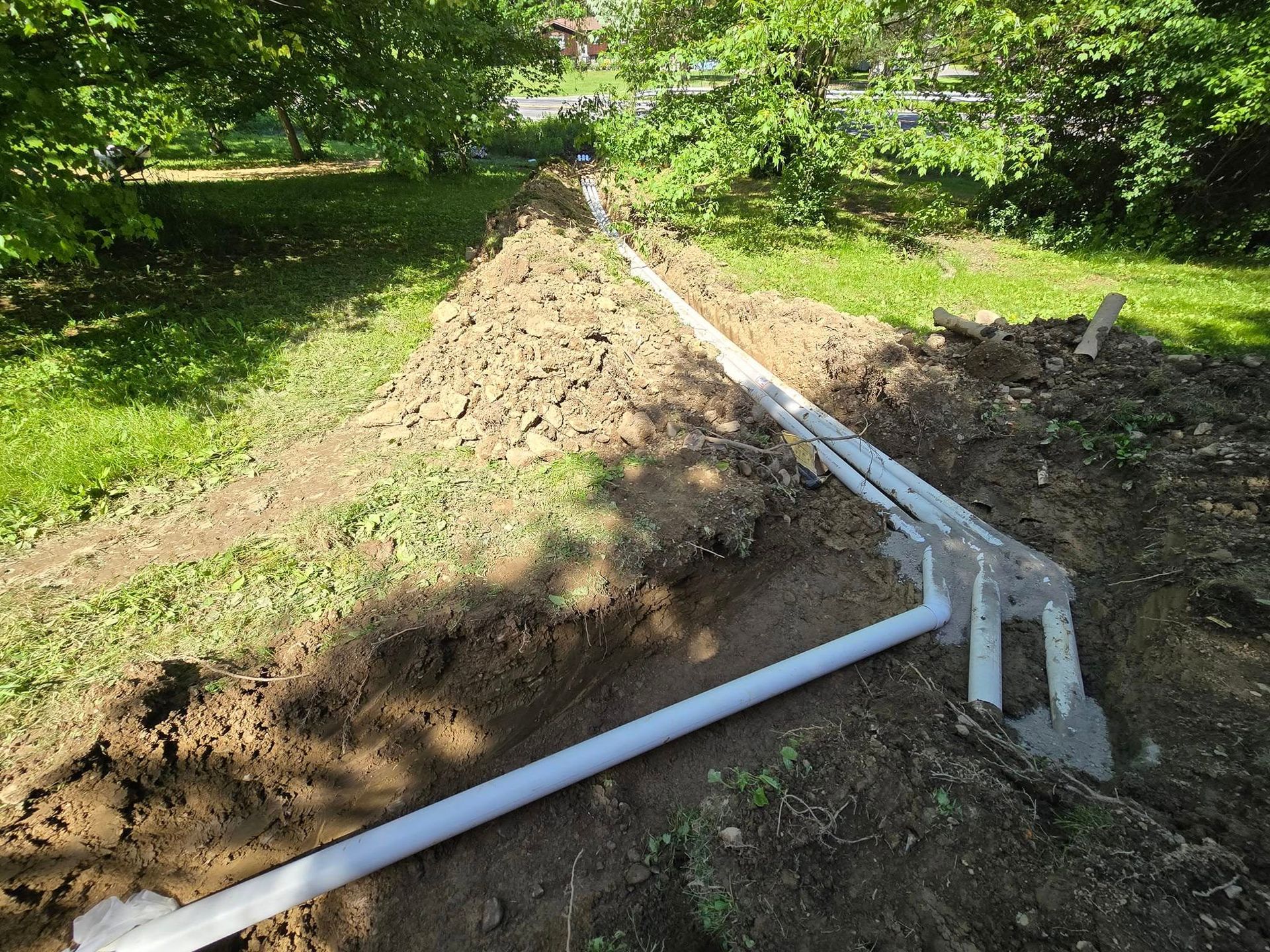 A bunch of pipes are laying in the dirt.