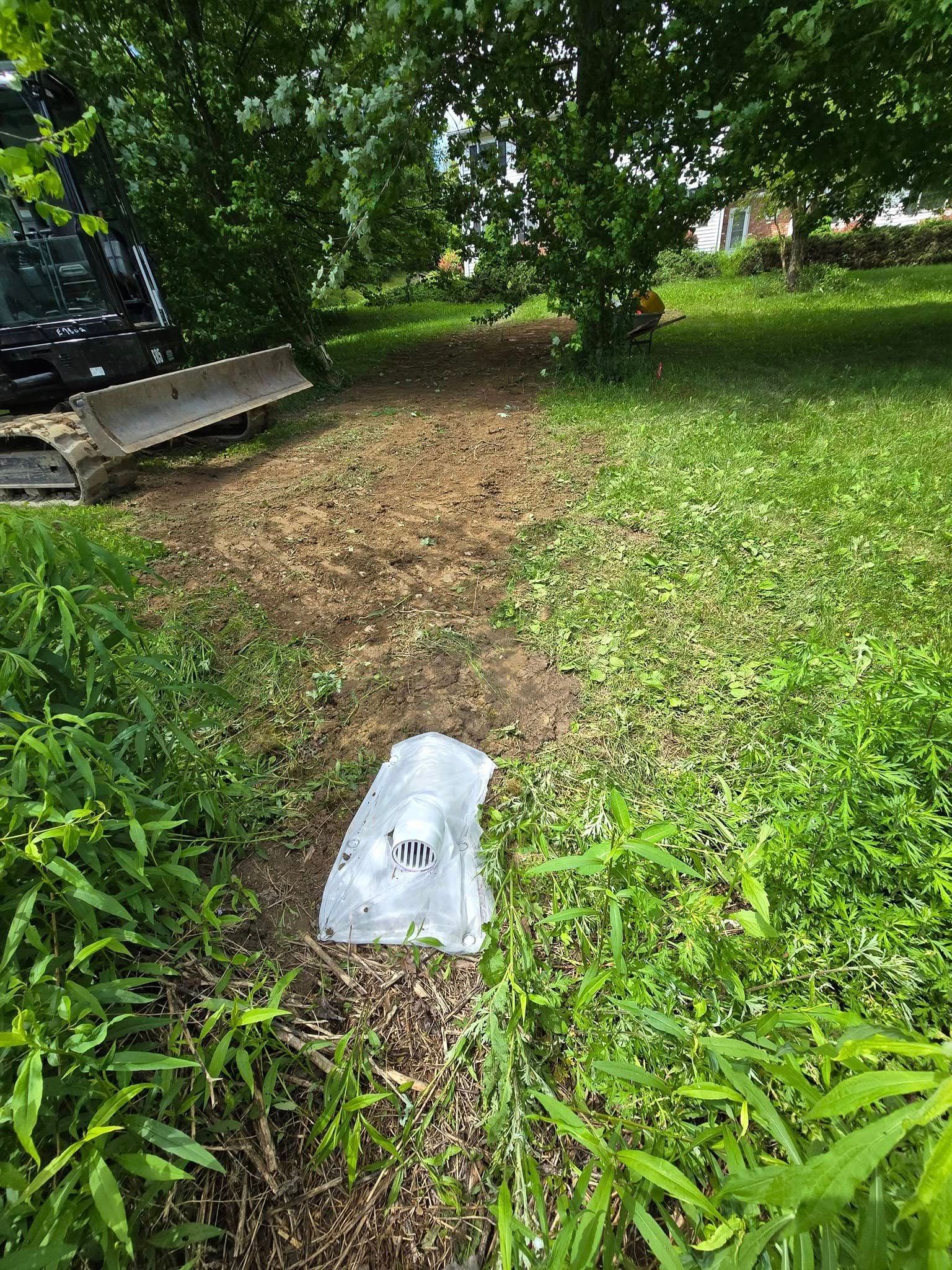 A white bag is laying in the grass next to a bulldozer.