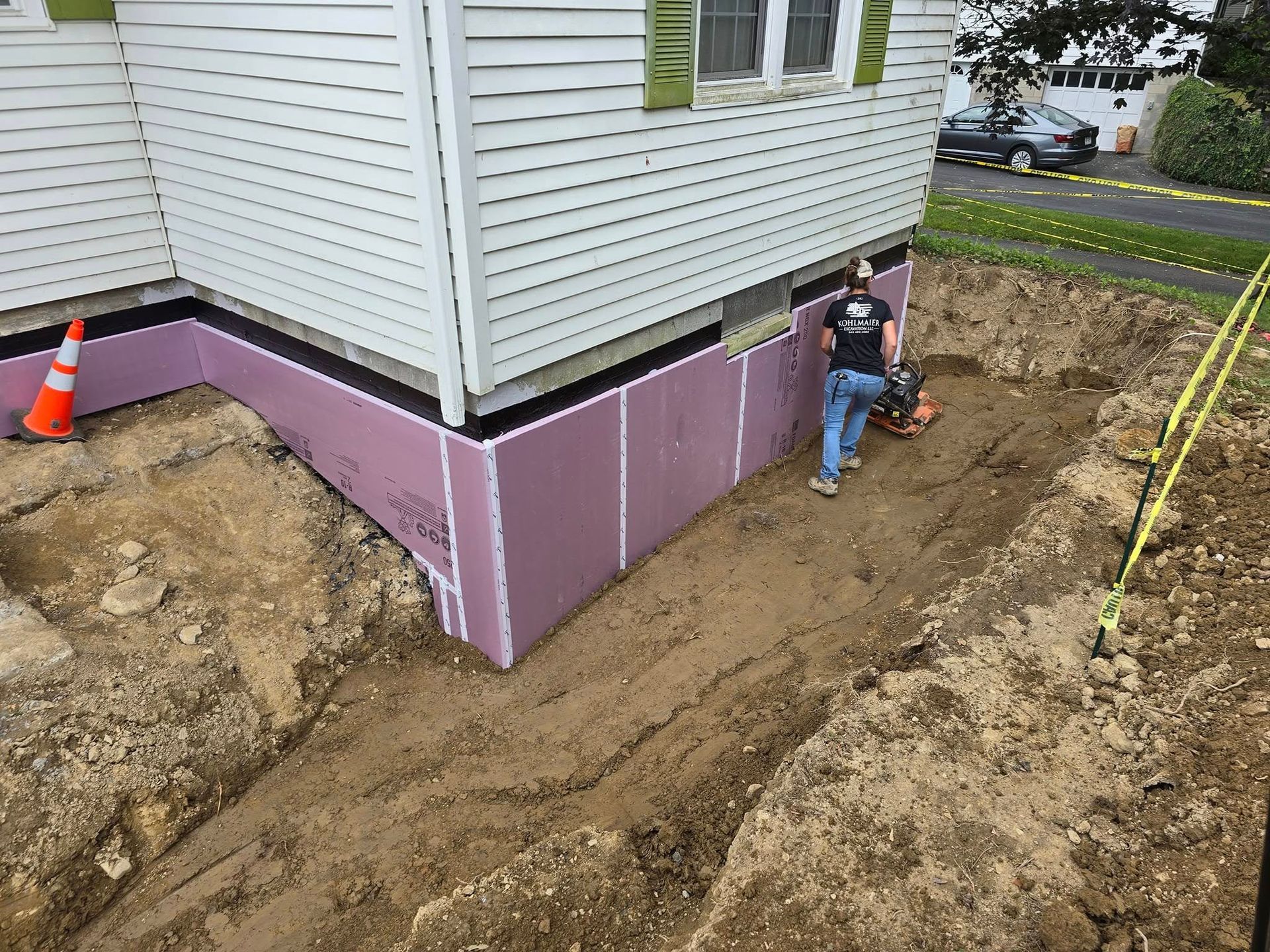 A man is digging a hole in front of a house.