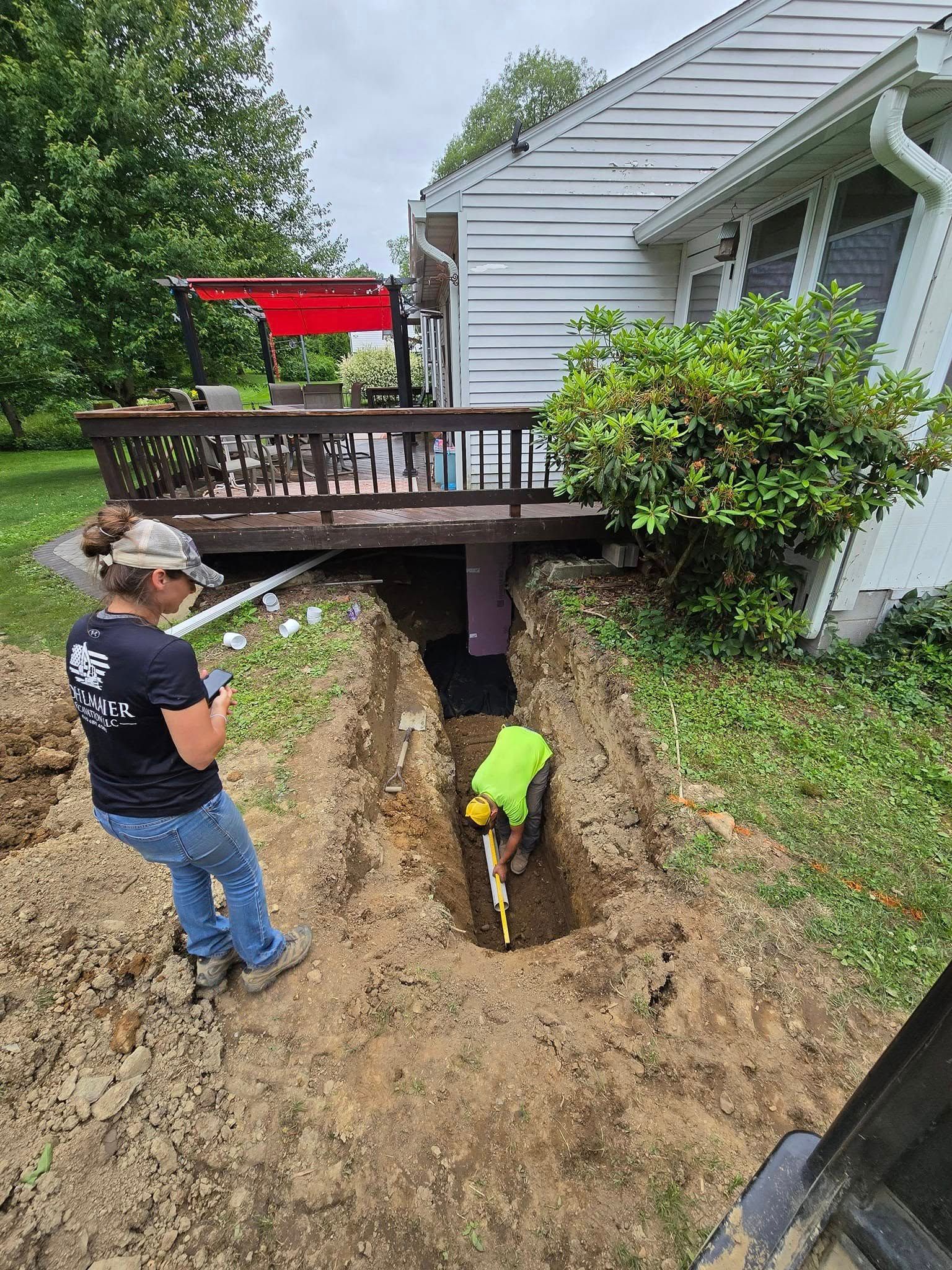 A man is digging a hole in the ground in front of a house.