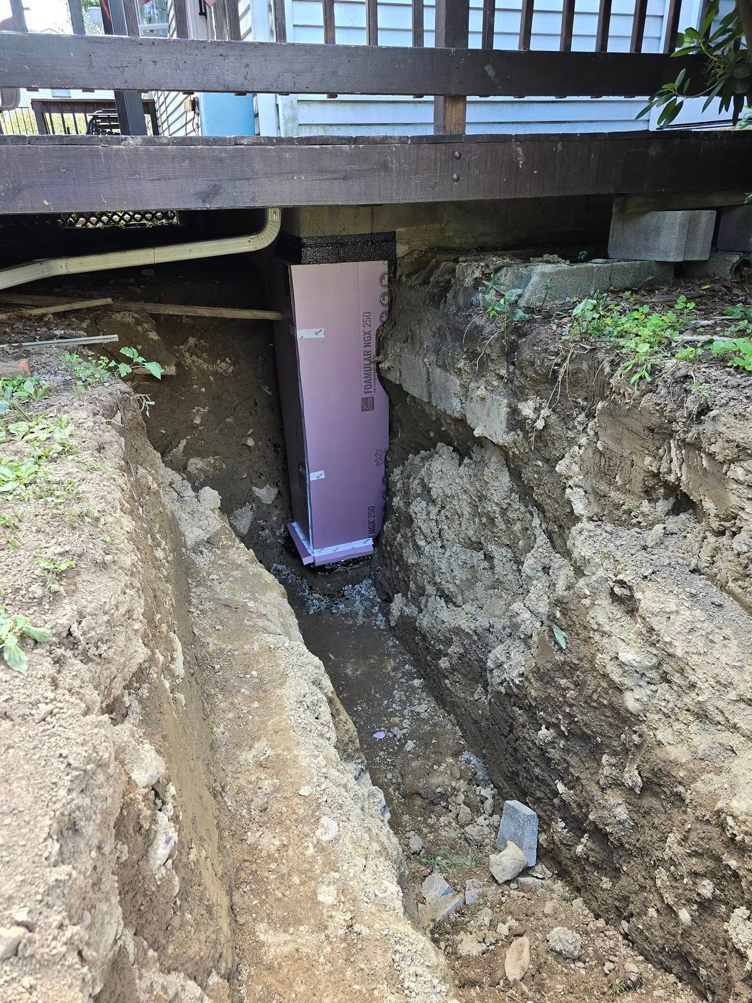 A hole in the ground next to a wooden fence.