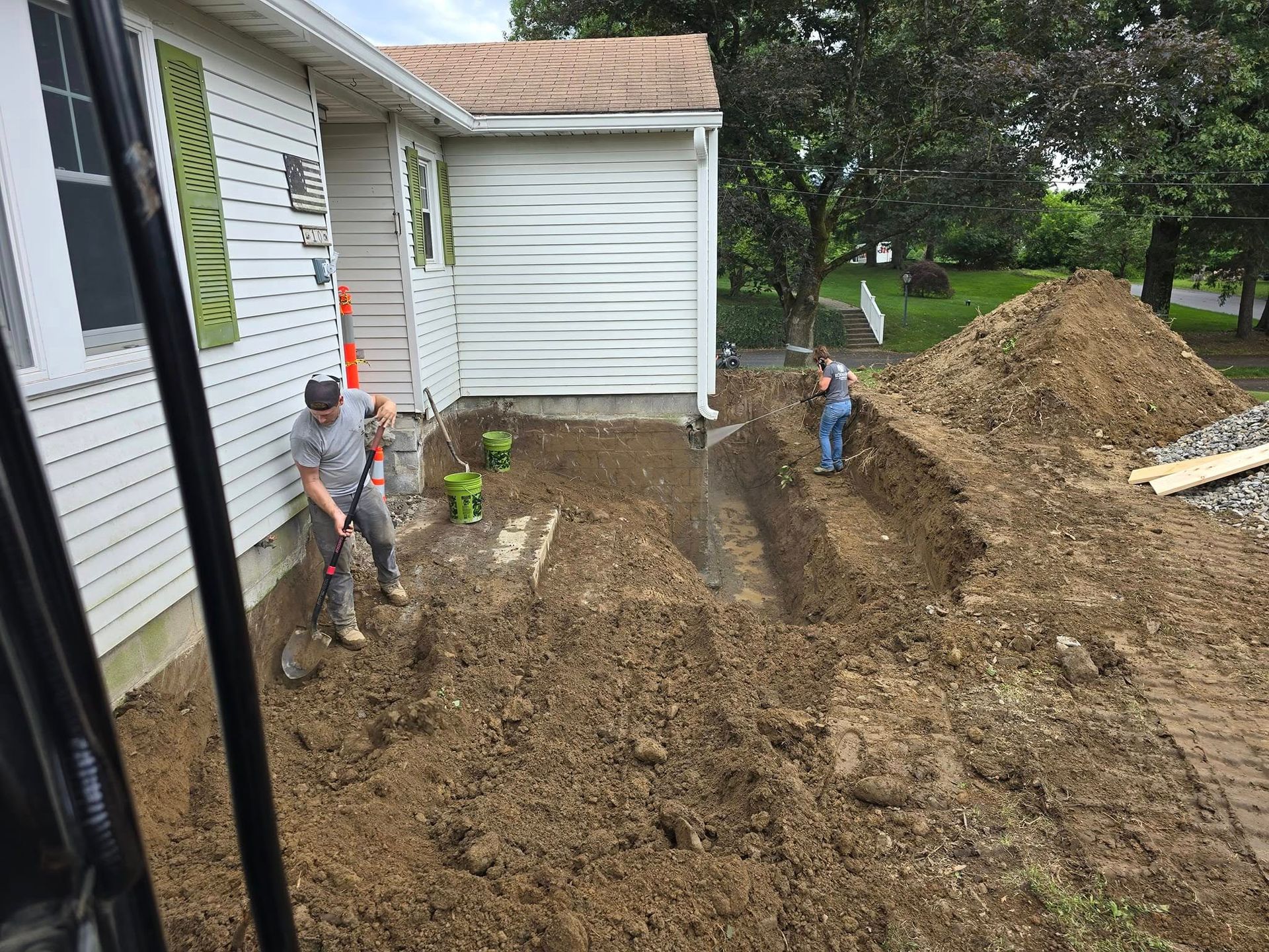 A man is digging in the dirt in front of a house.