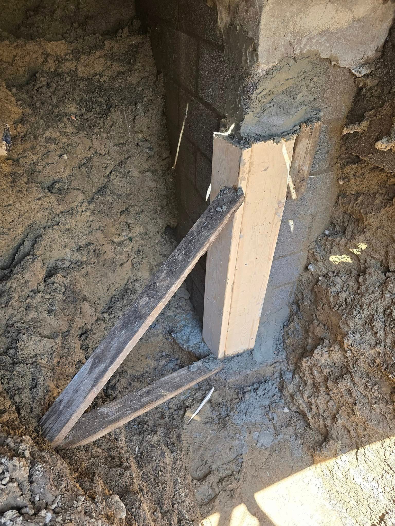 A wooden post is sitting on top of a pile of dirt.
