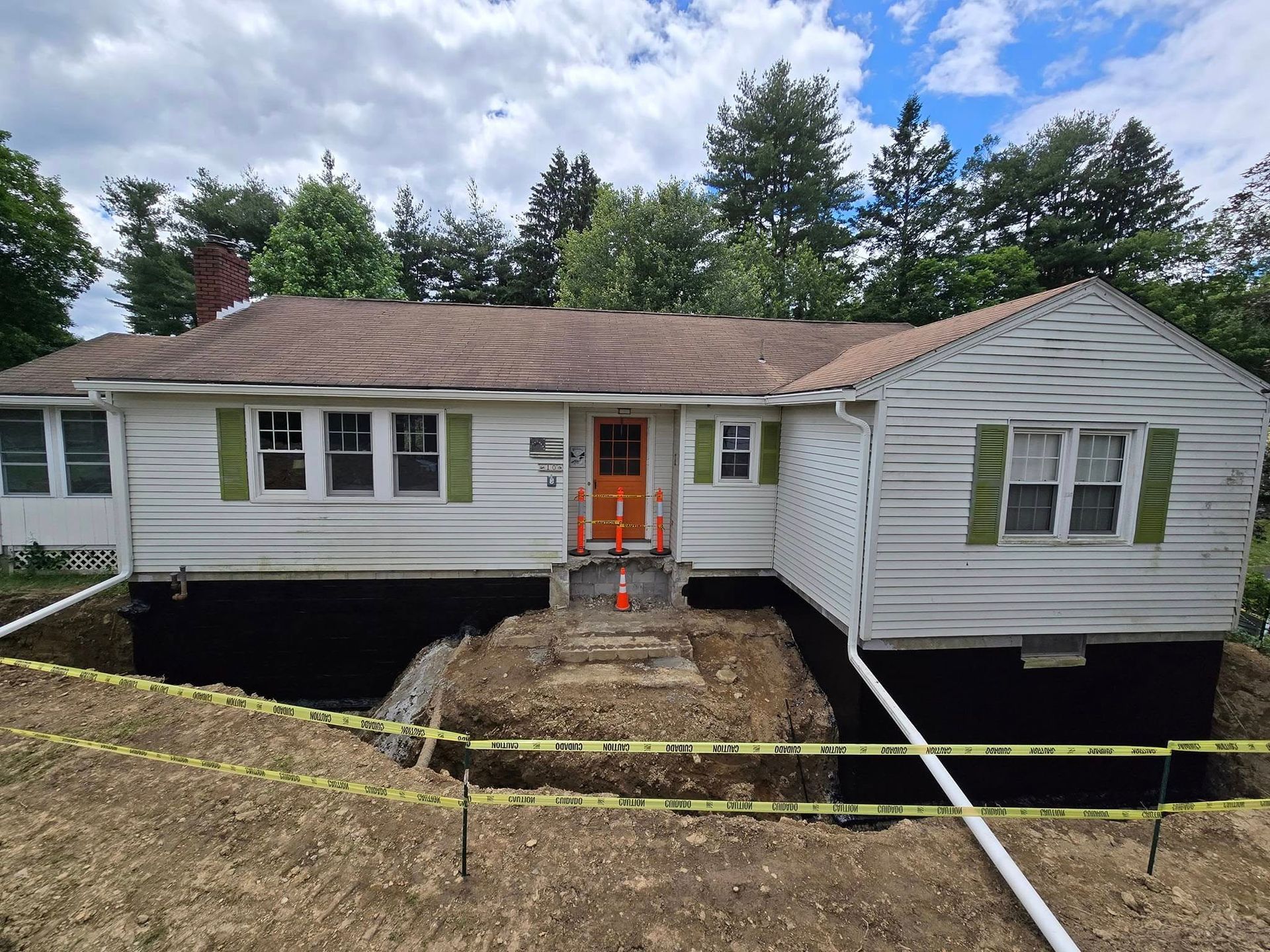 A white house with green shutters and an orange door