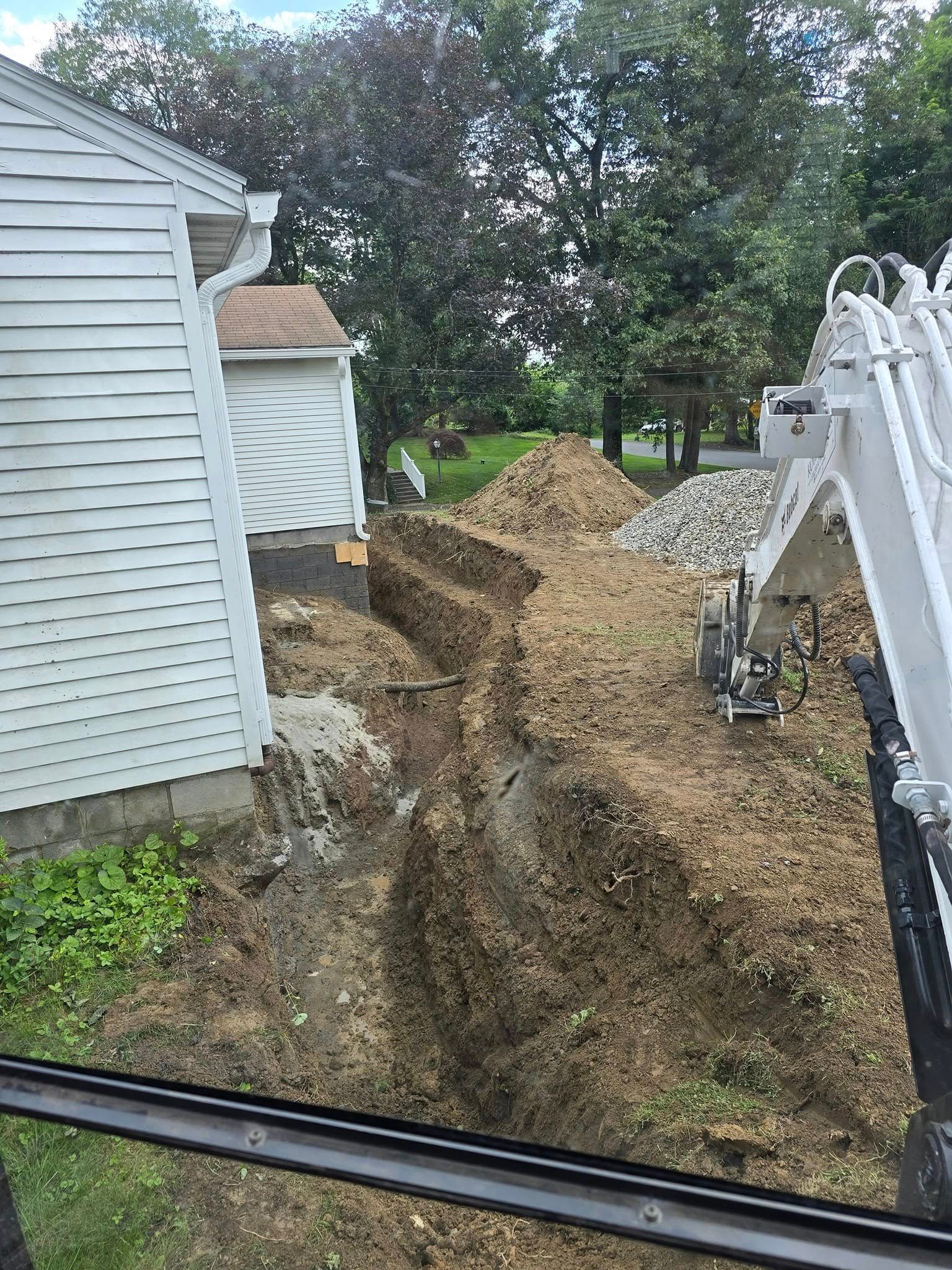 An excavator is digging a hole in front of a house.