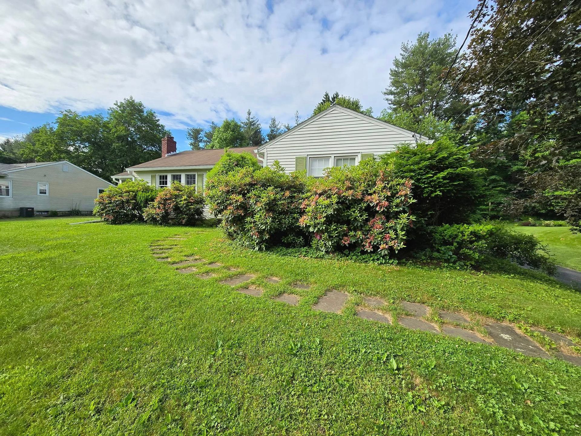 A house with a lot of grass and bushes in front of it.