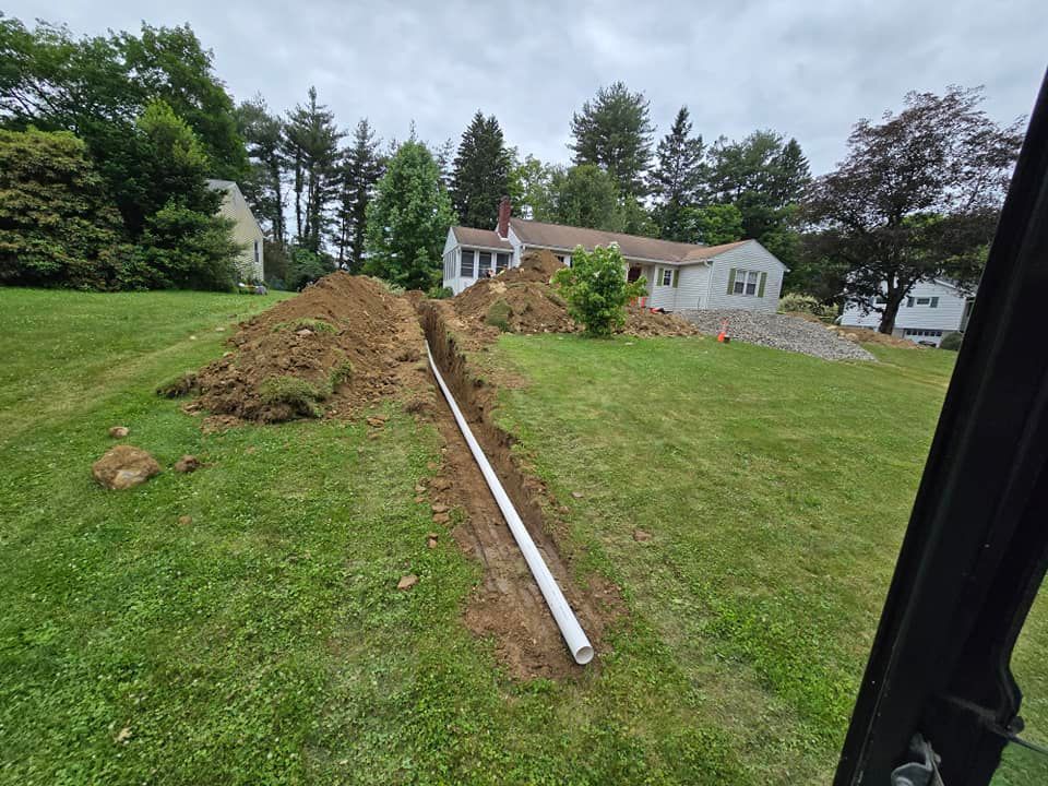 A pipe is being installed in a yard next to a house.