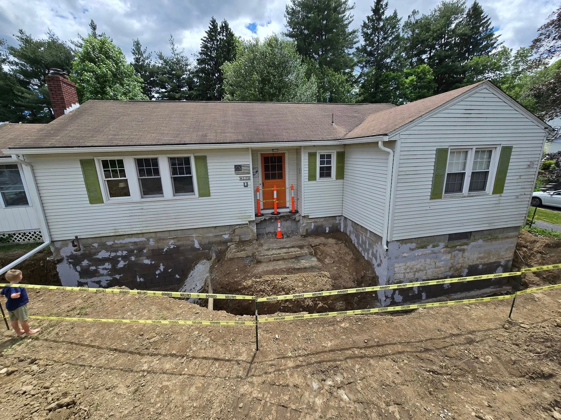 A white house with green shutters is being remodeled.