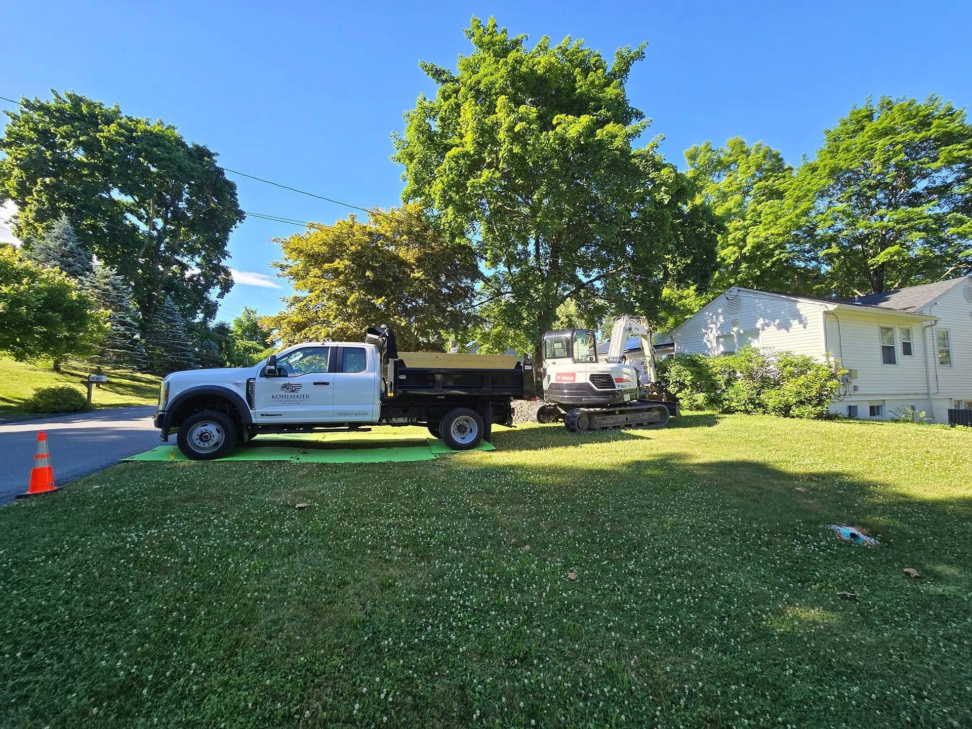 A white truck is parked in the grass in front of a house.