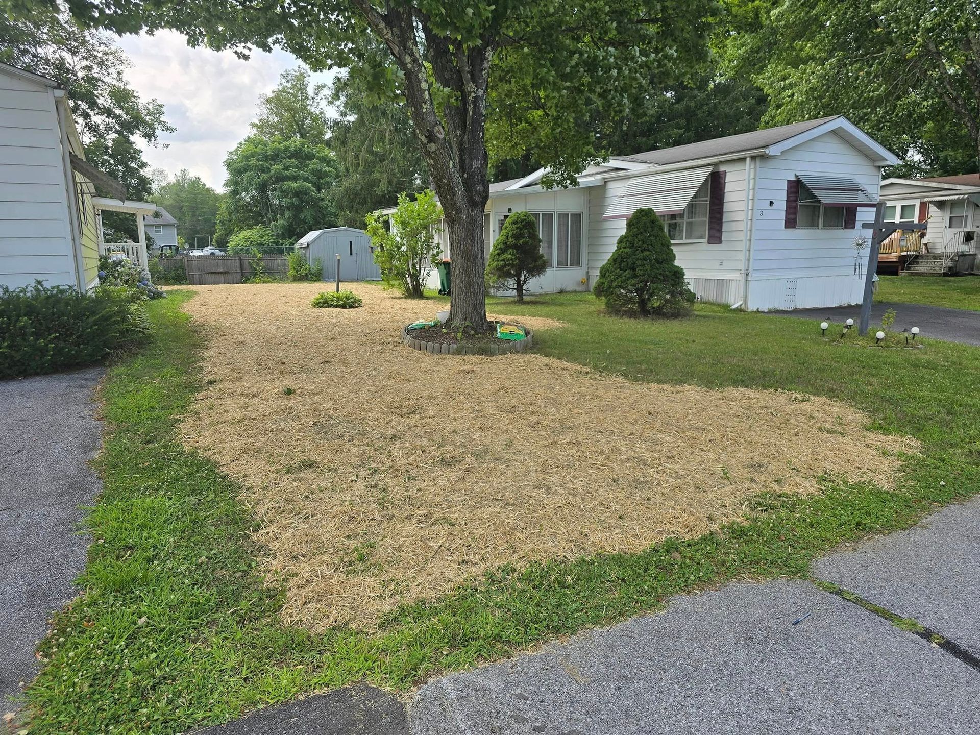 A mobile home with a lot of grass and dirt in front of it.
