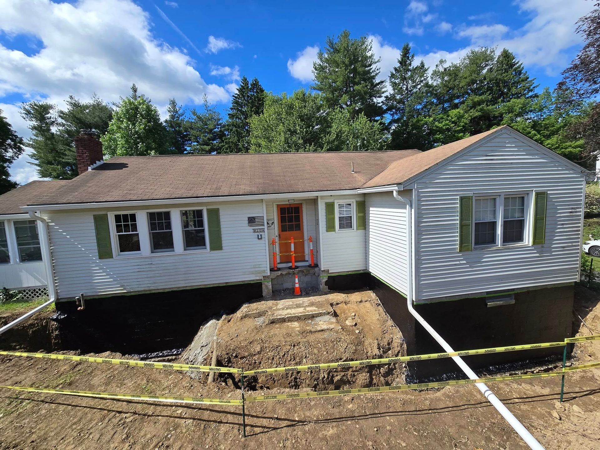 A white house with a brown roof is sitting on top of a dirt hill.
