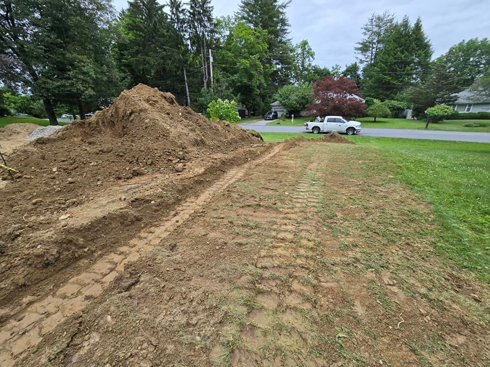 A white truck is driving down a dirt road next to a pile of dirt.